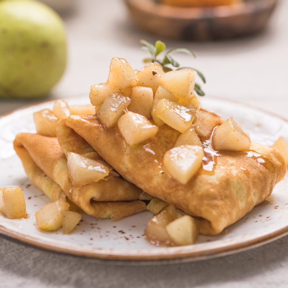 Thin pancakes (crepes) with apple filling, stuffed rolls, Russian traditional food for maslenitsa, French dessert, breakfast with tulips on mother's day
